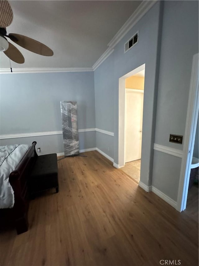 bedroom with crown molding, ceiling fan, baseboards, wood finished floors, and visible vents