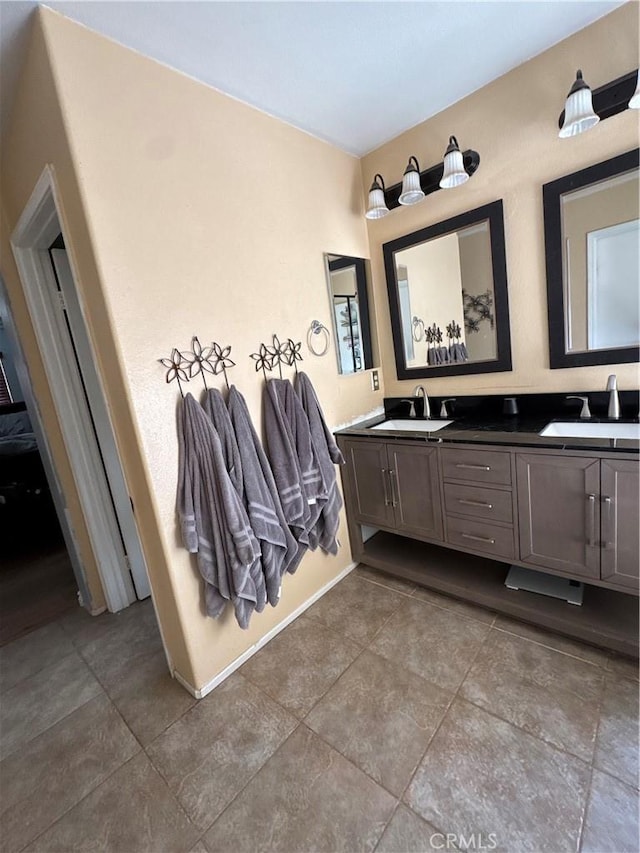 full bathroom with double vanity, a sink, baseboards, and tile patterned floors