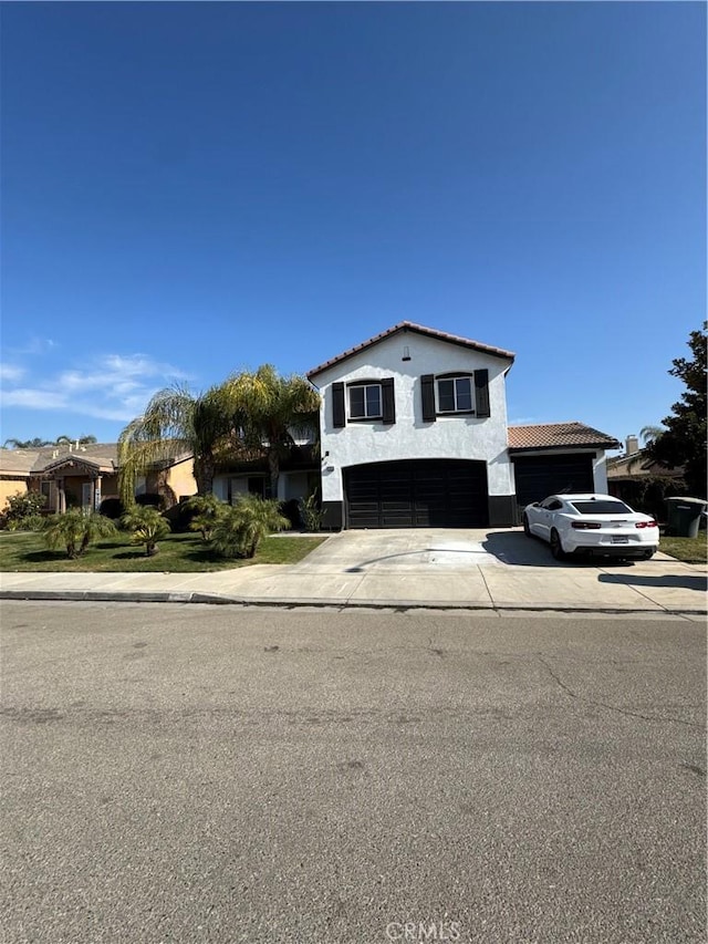 view of front of house with stucco siding, an attached garage, driveway, and a tile roof