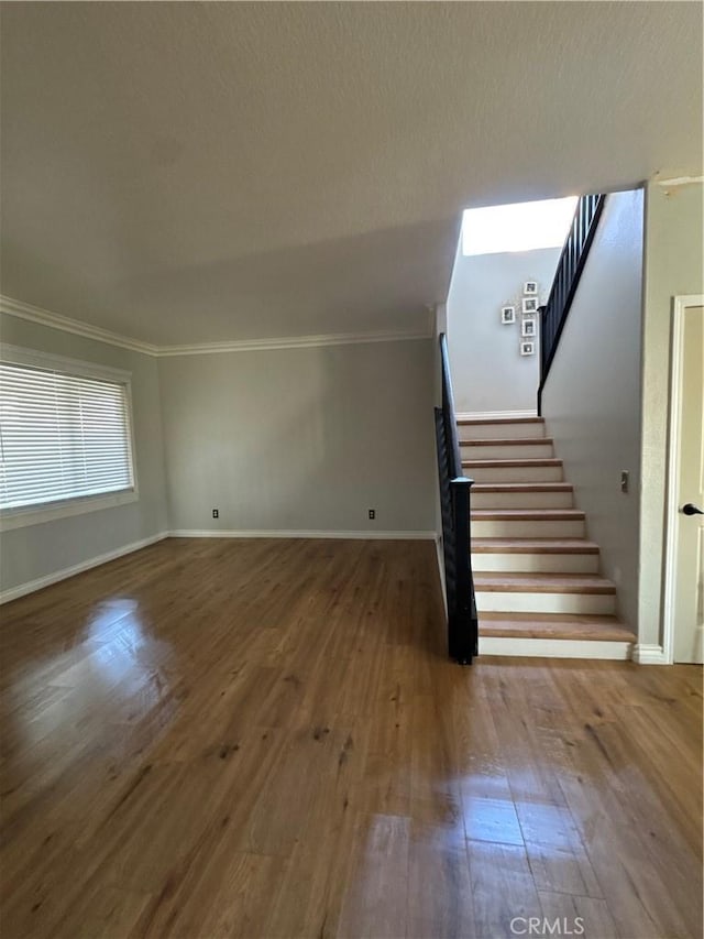 staircase featuring wood-type flooring and ornamental molding