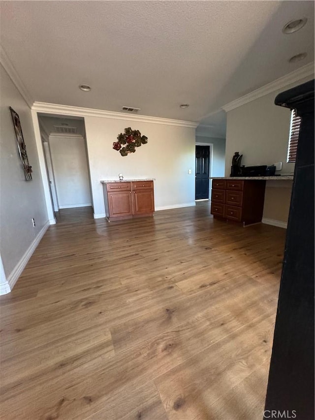 unfurnished living room featuring baseboards, ornamental molding, light wood finished floors, and visible vents