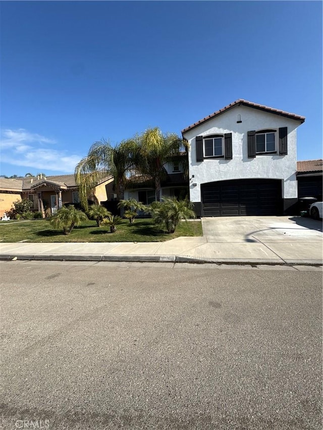view of front of house featuring a garage, stucco siding, a tiled roof, and concrete driveway