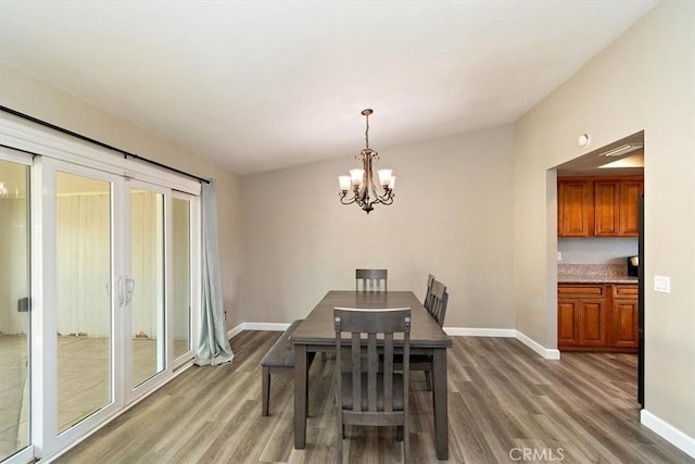 dining space with vaulted ceiling, a notable chandelier, and dark hardwood / wood-style flooring