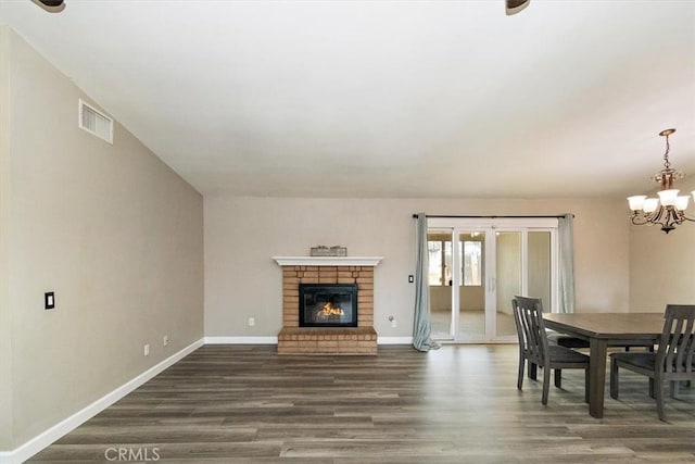 dining space featuring dark hardwood / wood-style flooring, a fireplace, and a chandelier