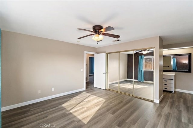 unfurnished bedroom featuring dark wood-type flooring, ceiling fan, and a closet