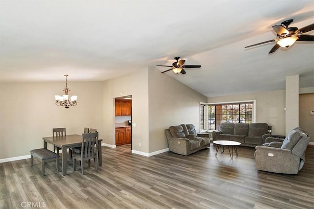 living room with ceiling fan with notable chandelier, dark wood-type flooring, and vaulted ceiling