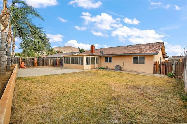 back of property with a patio, a sunroom, central AC, and a lawn