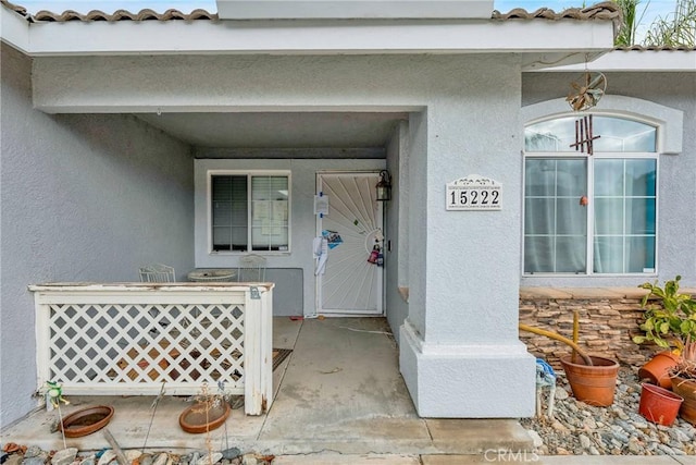 doorway to property featuring a tiled roof and stucco siding