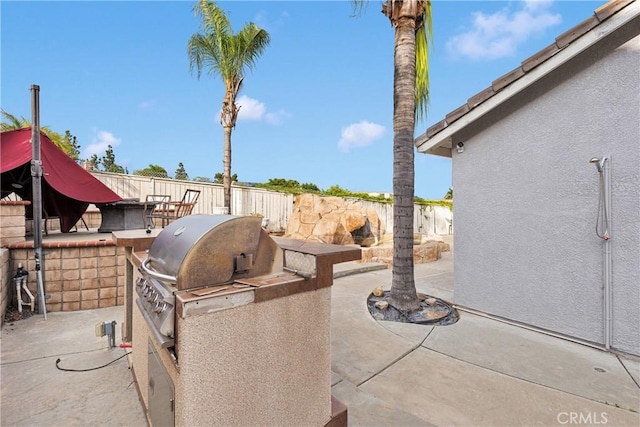 view of patio / terrace with grilling area, fence, and exterior kitchen