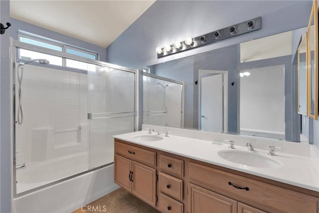 full bath featuring double vanity, combined bath / shower with glass door, and a sink
