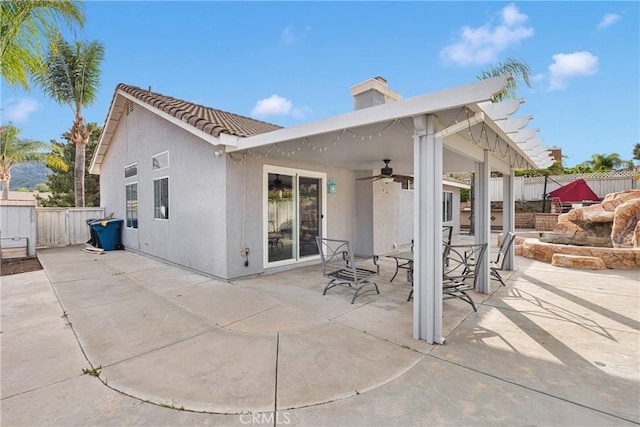 rear view of house featuring a chimney, a fenced backyard, stucco siding, ceiling fan, and a patio area
