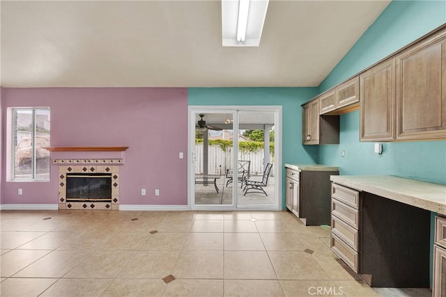 kitchen featuring lofted ceiling, baseboards, a fireplace, and light tile patterned floors