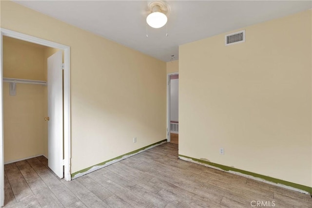 unfurnished bedroom with baseboards, wood finished floors, and visible vents