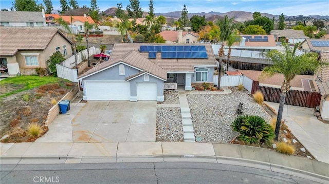 view of front of property featuring a residential view, a fenced backyard, solar panels, concrete driveway, and stucco siding