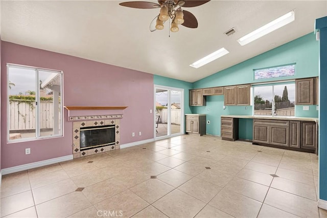 kitchen with vaulted ceiling, visible vents, light tile patterned flooring, baseboards, and ceiling fan