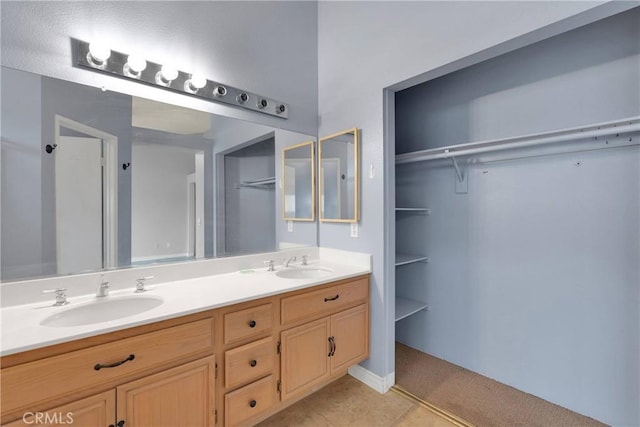 full bathroom featuring a walk in closet, double vanity, tile patterned floors, and a sink