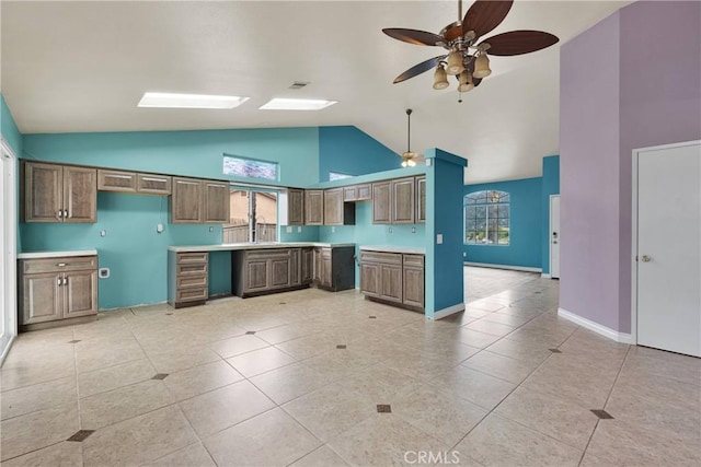 kitchen with light tile patterned flooring, baseboards, ceiling fan, light countertops, and high vaulted ceiling