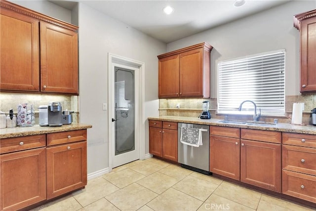 kitchen with light stone counters, dishwasher, a sink, and tasteful backsplash