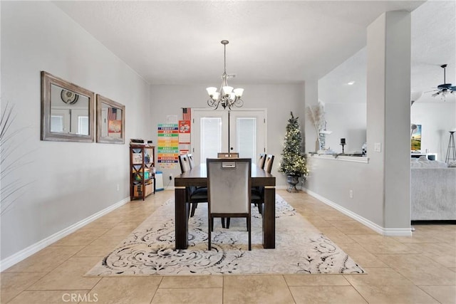 dining space with light tile patterned floors, ceiling fan with notable chandelier, and baseboards