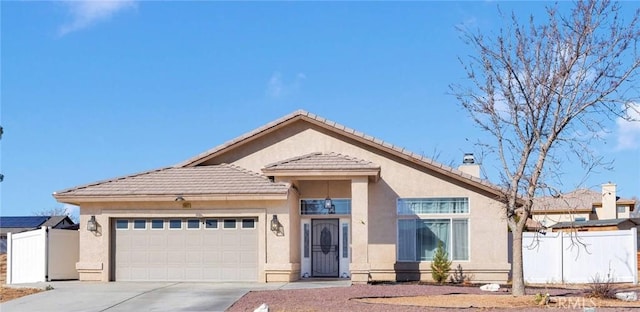 view of front of home with a garage, driveway, fence, and stucco siding