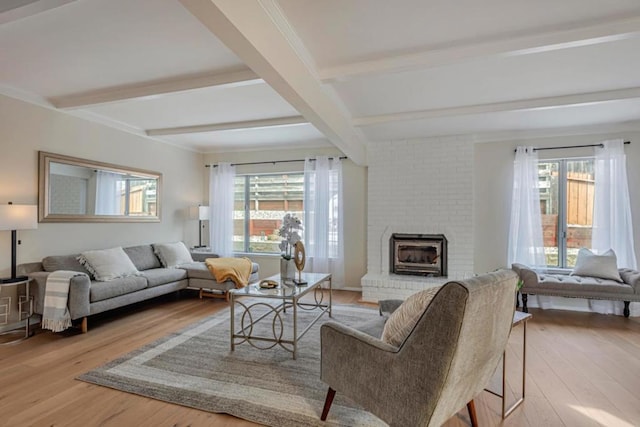 living room featuring a fireplace, a wealth of natural light, light hardwood / wood-style floors, and beamed ceiling