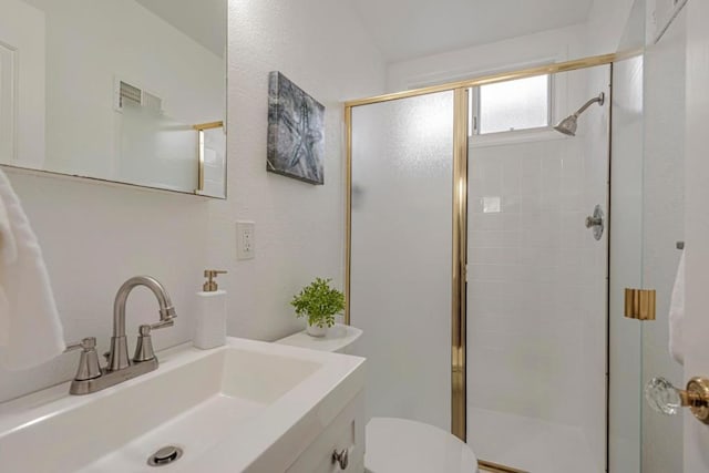 bathroom with vanity, a shower with shower door, and toilet