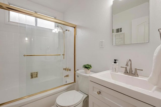 full bathroom featuring vanity, combined bath / shower with glass door, and toilet