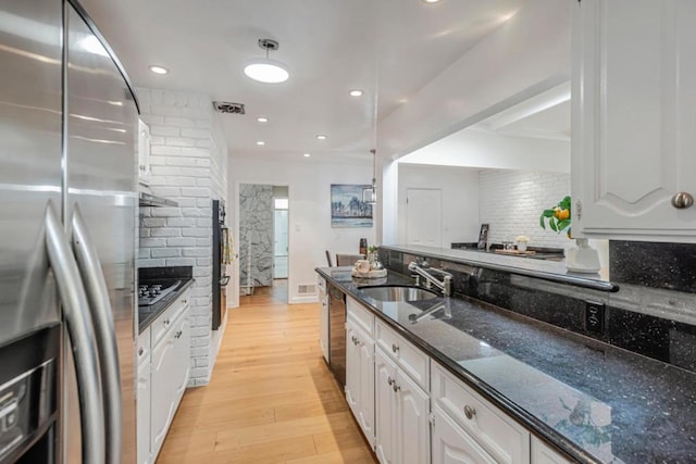 kitchen featuring sink, white cabinets, backsplash, dark stone counters, and stainless steel appliances