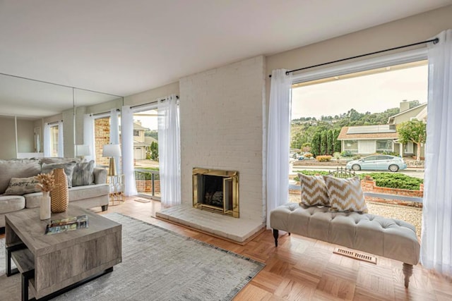 living room featuring light parquet floors, a brick fireplace, and a wealth of natural light