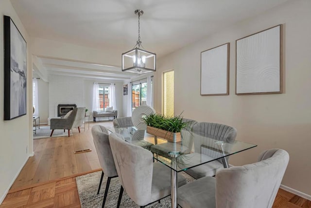 dining room with an inviting chandelier, a brick fireplace, and light parquet flooring