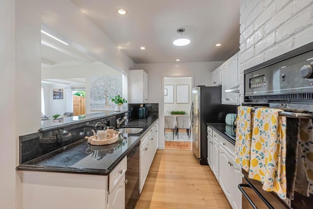 kitchen with sink, white cabinetry, dark stone countertops, black appliances, and light wood-type flooring