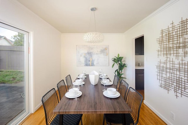 dining area featuring ornamental molding, a chandelier, and light hardwood / wood-style floors