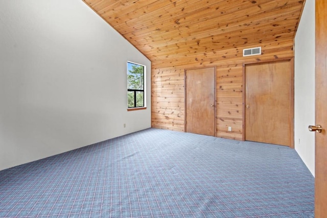 unfurnished bedroom featuring wooden walls, vaulted ceiling, carpet, and wooden ceiling