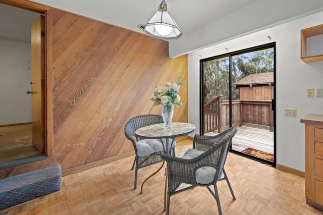 dining room with light parquet flooring and wooden walls