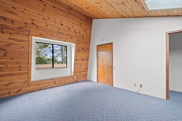 unfurnished bedroom with wood ceiling, lofted ceiling with skylight, carpet floors, and wood walls