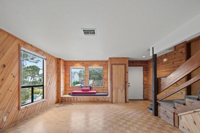 interior space with a healthy amount of sunlight, light parquet flooring, and wooden walls