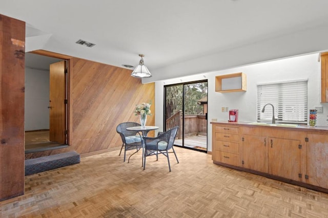 dining area featuring sink, light parquet flooring, and wood walls