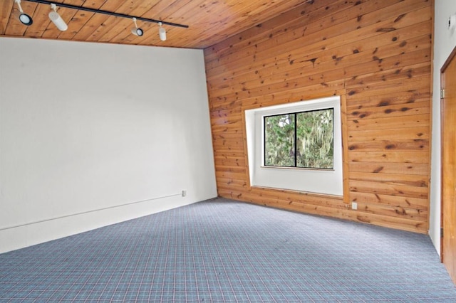 spare room with vaulted ceiling, wooden walls, carpet, wood ceiling, and track lighting