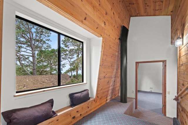 living area with wood ceiling, carpet, and wood walls