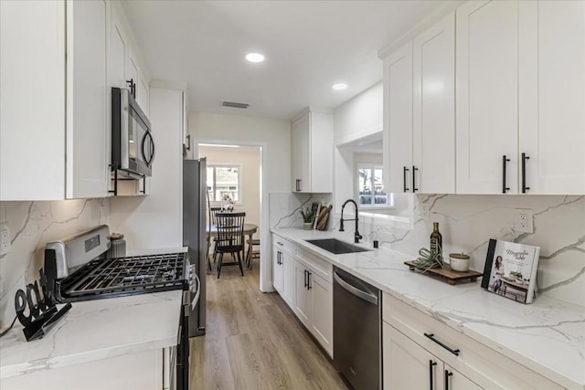 kitchen featuring light stone counters, appliances with stainless steel finishes, sink, and white cabinets