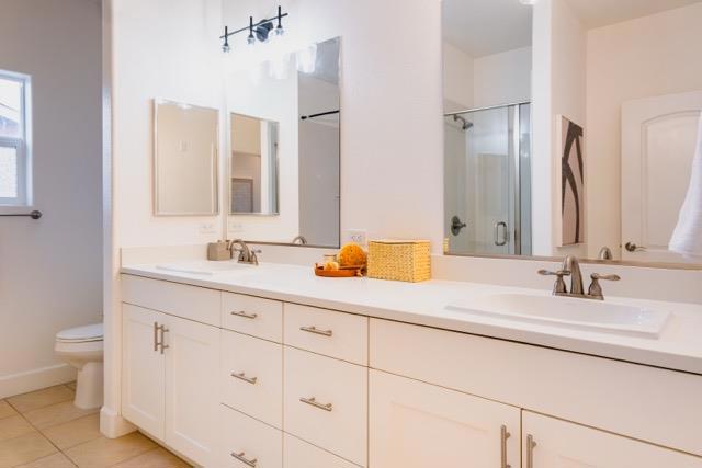 bathroom featuring tile patterned flooring, vanity, a shower with shower door, and toilet