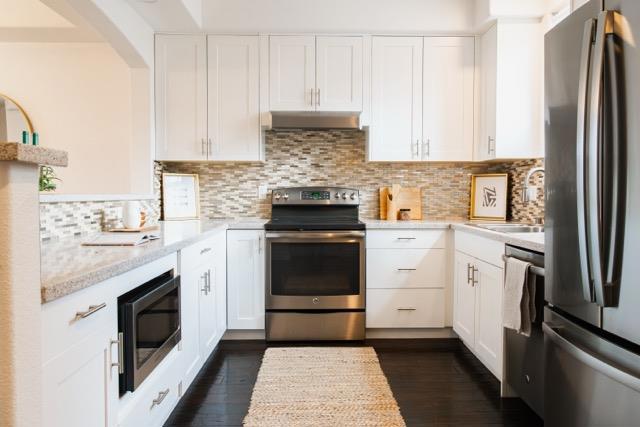 kitchen featuring backsplash, stainless steel appliances, light stone countertops, white cabinets, and dark hardwood / wood-style flooring