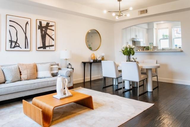 living room featuring an inviting chandelier and dark hardwood / wood-style floors