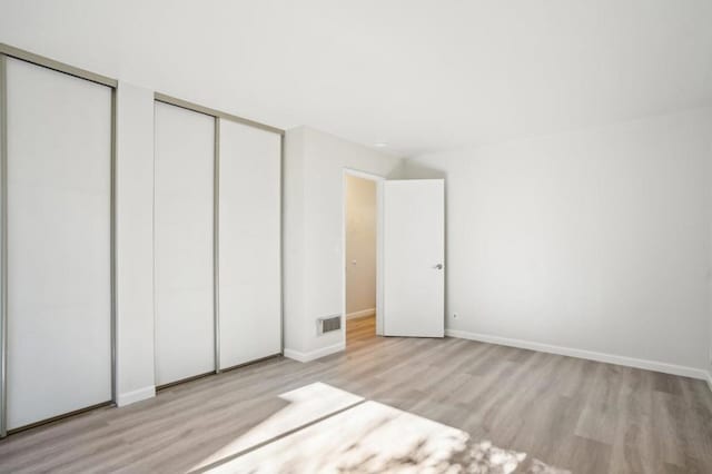 unfurnished bedroom with multiple closets and light wood-type flooring