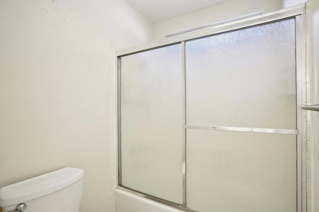 bathroom featuring enclosed tub / shower combo and toilet