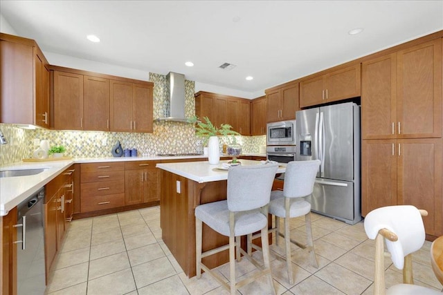 kitchen featuring appliances with stainless steel finishes, sink, a kitchen breakfast bar, a center island, and wall chimney range hood