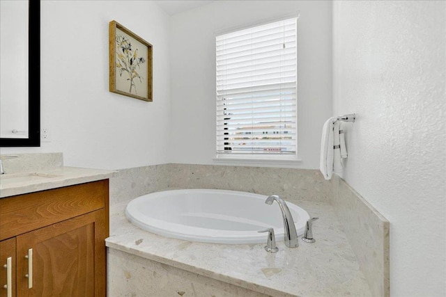 bathroom featuring vanity and tiled tub