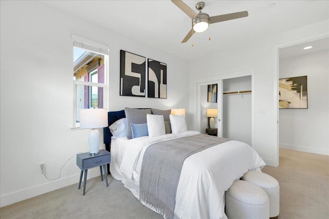 bedroom with light colored carpet, ceiling fan, and a closet