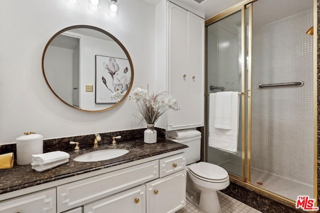 bathroom featuring vanity, a shower with shower door, tile patterned floors, and toilet