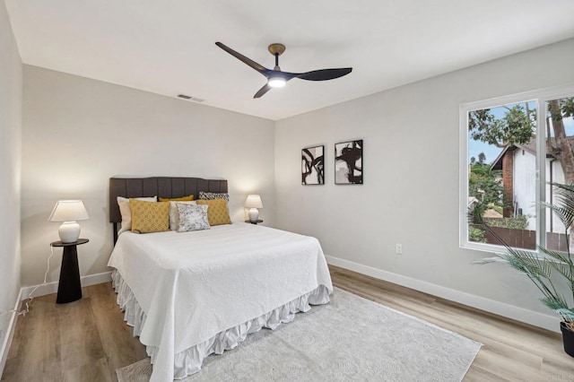 bedroom featuring light wood finished floors, a ceiling fan, visible vents, and baseboards